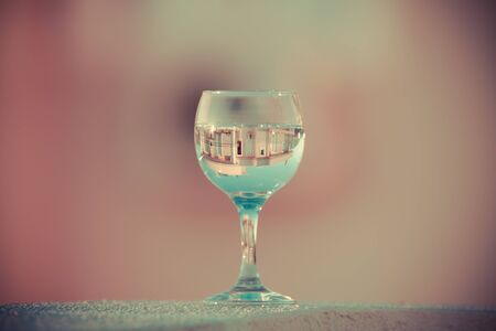 The wineglass with reflection of building on a blurred background. Selective focus. Toned.