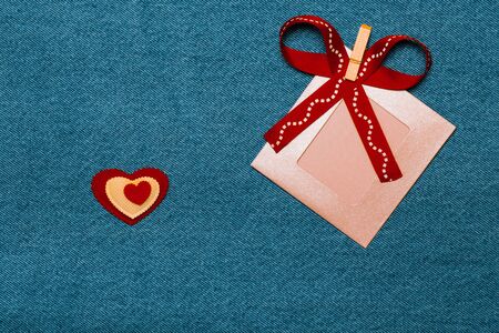 Textile heart, ribbon and pink photo frame. Romantic love theme on jeans background. Toned.
