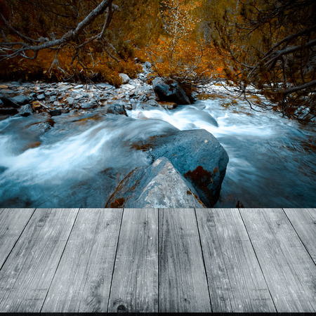 Stormy water of a mountain river in the forest. View from dark wooden gangway, table or bridge. Collage. Selective focus. Toned.の写真素材