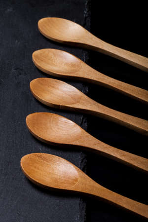 Wooden spoons on a plate of slate on a black background.