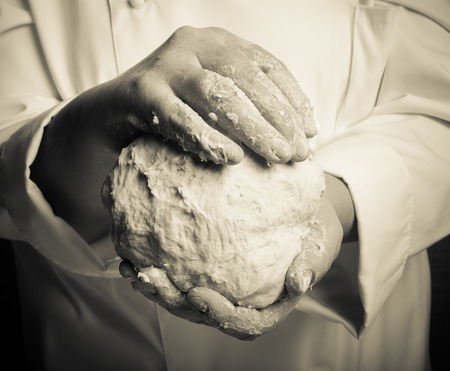 Raw dough in a chef hands. Toned.