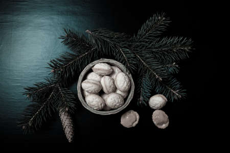Cookies Nuts with sweet filling in a wicker basket with Christmas tree branches on a black...