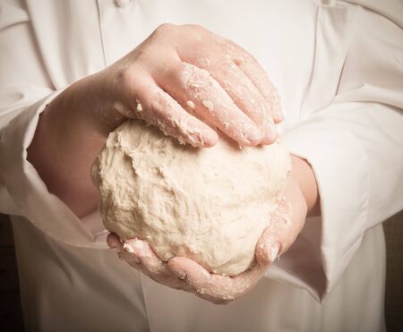 Raw dough in a chef hands. Toned.