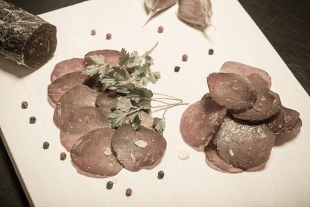 Sliced horse sausage, herbs and spices on cutting board. Selective focus. Toned.の写真素材