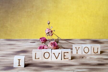 Wooden cubes and dry rose flowers on new wooden board and burlap background.の写真素材