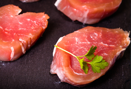 Raw meat with herbs and spices on a black slate plate. Selective focus. Toned.の写真素材