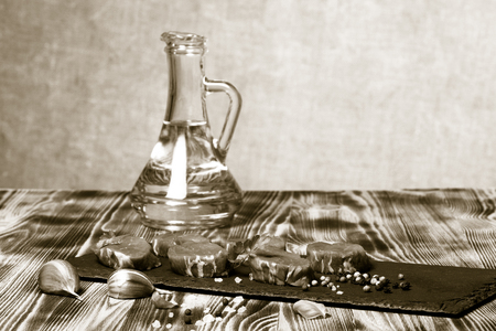 Raw meat with herbs and spices on a black slate plate on a wooden table in front burlap background. Selective focus. Toned.の写真素材