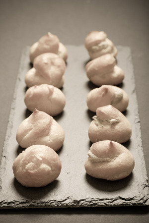 Set of small profiteroles on a black slate plate. Selective focus. Shallow depth of field. Toned.の写真素材