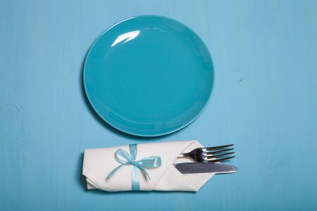 Plate, fork and knife in napkin on wooden background.の写真素材