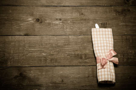 Fork and knife in napkin on wooden background. Toned.の写真素材