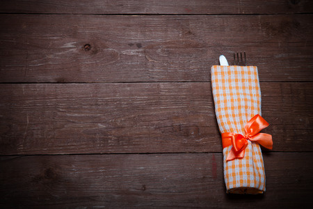 Fork and knife in napkin on wooden background. Toned.の写真素材