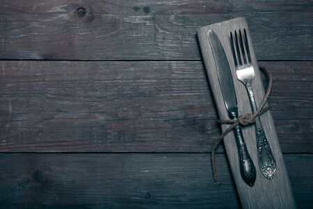 Fork and knife in napkin on wooden background. Toned.の写真素材