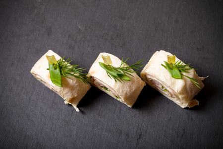 Small rolls with ham, cheese and pita on skewer on a black slate plate. Toned.の写真素材