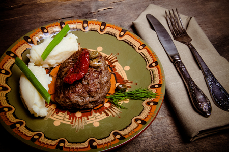 Homemade cutlet with mashed potatoes on a plate on old wooden table. Toned.の写真素材