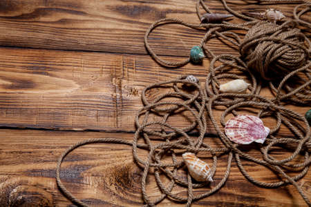 Rope and seashells on old wooden burned table or board for background.の写真素材
