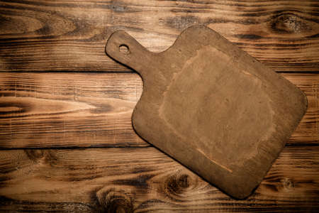 Retro cutting board on old wooden burned table or board for background. Toned.