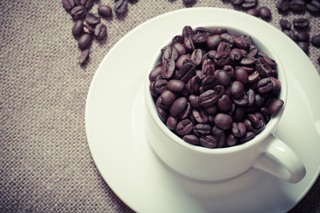 Cup, saucer and coffee beans on a burlap background. Selective focus. Toned.の写真素材