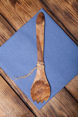 Blue kitchen towel and wooden spoon on old wooden burned table or board for background.の写真素材