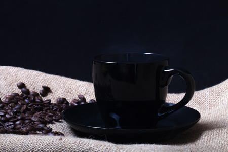 Cup, saucer and coffee beans on a burlap background.の写真素材