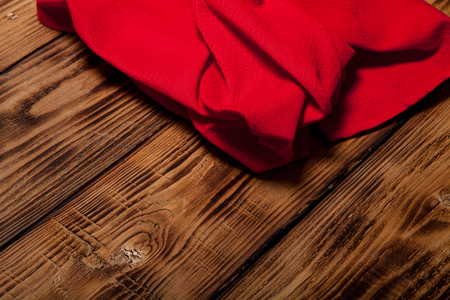 Red kitchen towel on old wooden burned table or board for background.