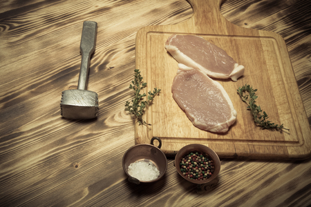 Fresh meat steaks on light wooden cutting board. Selective focus. Toned.
