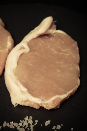 Fresh meat steaks on black slate background. Selective focus. Toned.の写真素材