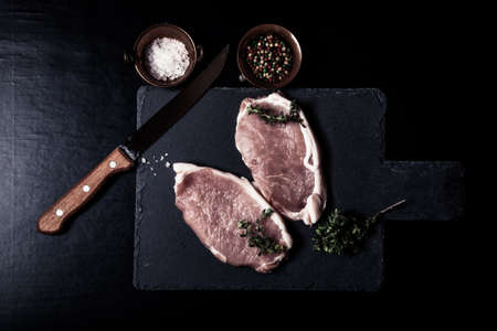 Fresh meat steaks on black slate background. Toned.の写真素材