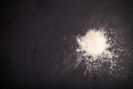 Flour spilling on color background of slate cutting board. Toned.の写真素材