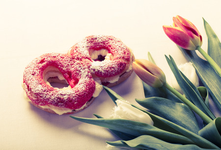 Homemade custard cakes with cream and bunch of spring tulips on the table. Toned.の写真素材