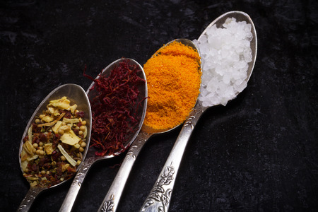 Ancient melchior spoons with spices on metal surface for background. Toned.の写真素材
