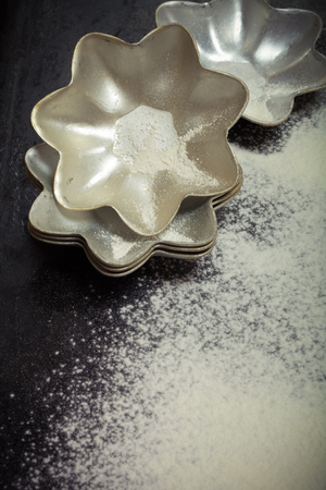 Baking forms and sprinkle flour on black background. Toned.の写真素材