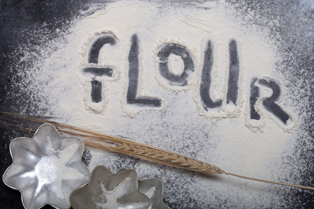 Inscription on sprinkle flour on black background.の写真素材