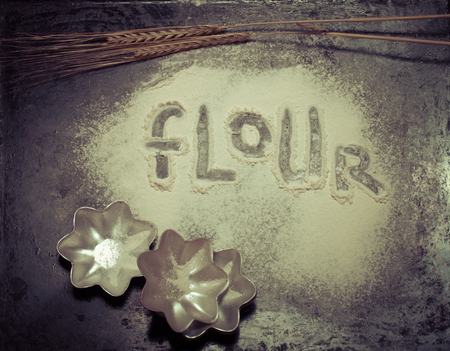 Inscription on sprinkle flour on black background. Toned.の写真素材