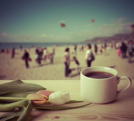 Tea cup with tulips on the wooden table opposite blurred background. Collage. Selective Focus. Toned.の写真素材
