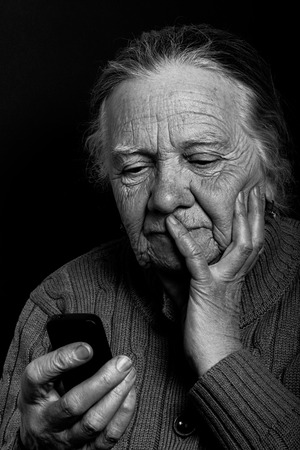 Portrait of elderly woman with telephone on dark background. Toned.の写真素材