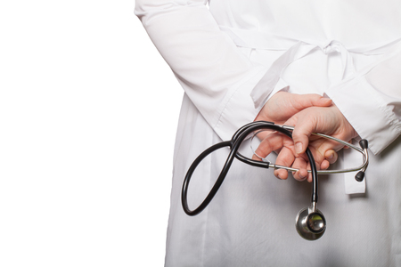 The doctor put his hands with stethoscope behind his back on a white background.の写真素材