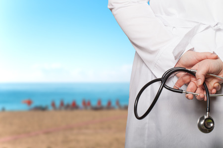 The doctor put his hands with stethoscope behind his back on a blurred background.の写真素材