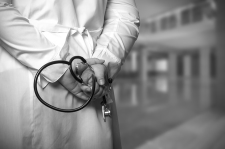 The doctor put his hands with stethoscope behind his back on a blurred background. Toned.の写真素材