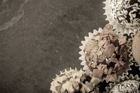 Round homemade chocolates in different kind of decor on paper substrates. Space for text. Toned.の写真素材