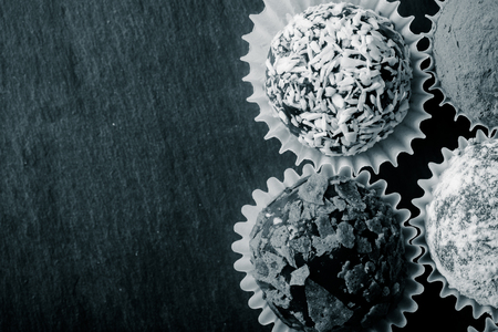 Round homemade chocolates in different kind of decor on paper substrates. Space for text. Toned.の写真素材