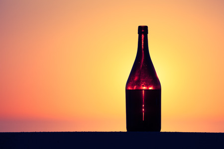 Bottle of white vine with reflections of houses and view to beautiful sunset. Selective focus. Toned.の写真素材