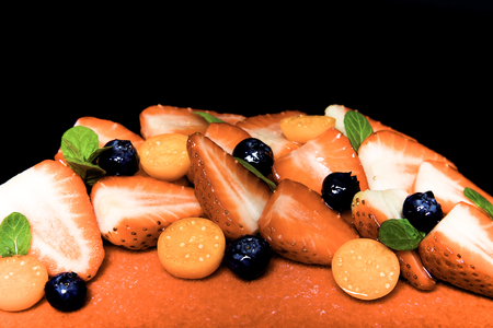 Many fresh berries on bright mousse cake. Toned.