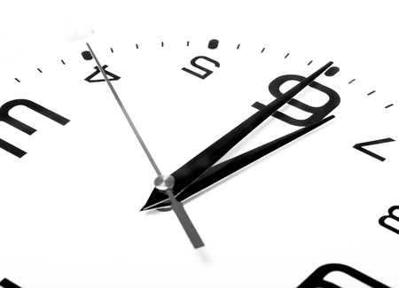 White wall clock with black arrows. Selective focus. Shallow depth of field. Toned.