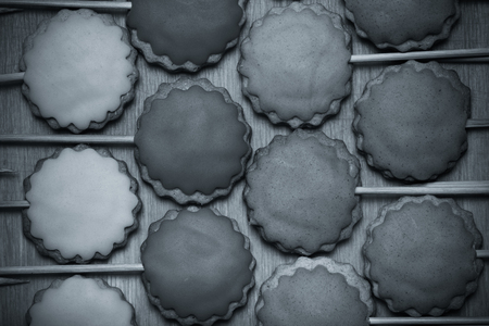 Gingerbread cookies with colored mastic on sticks on the old wooden cutting board. Toned.の写真素材