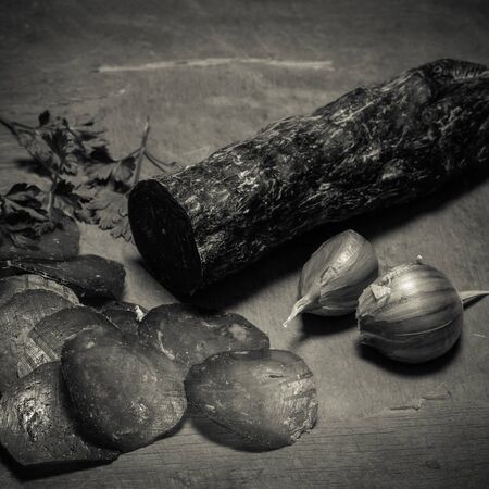 Sliced horse sausage, herbs and spices on cutting board. Selective focus. Shallow depth of field. Toned.の写真素材