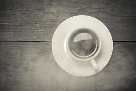 White cup of coffee on old wooden table. Toned.の写真素材