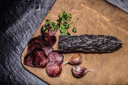 Sliced horse sausage, herbs and spices on cutting board. Toned.の写真素材