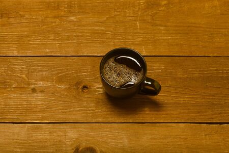 Black cup of coffee on old wooden table. Toned.の写真素材