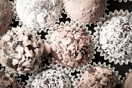 Round homemade chocolates in different kind of decor on paper substrates. Toned.の写真素材