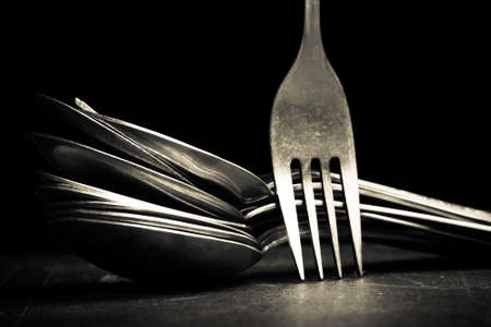 Lot of metal cutlery on a black background. Selective focus. Shallow depth of field. Toned.の写真素材